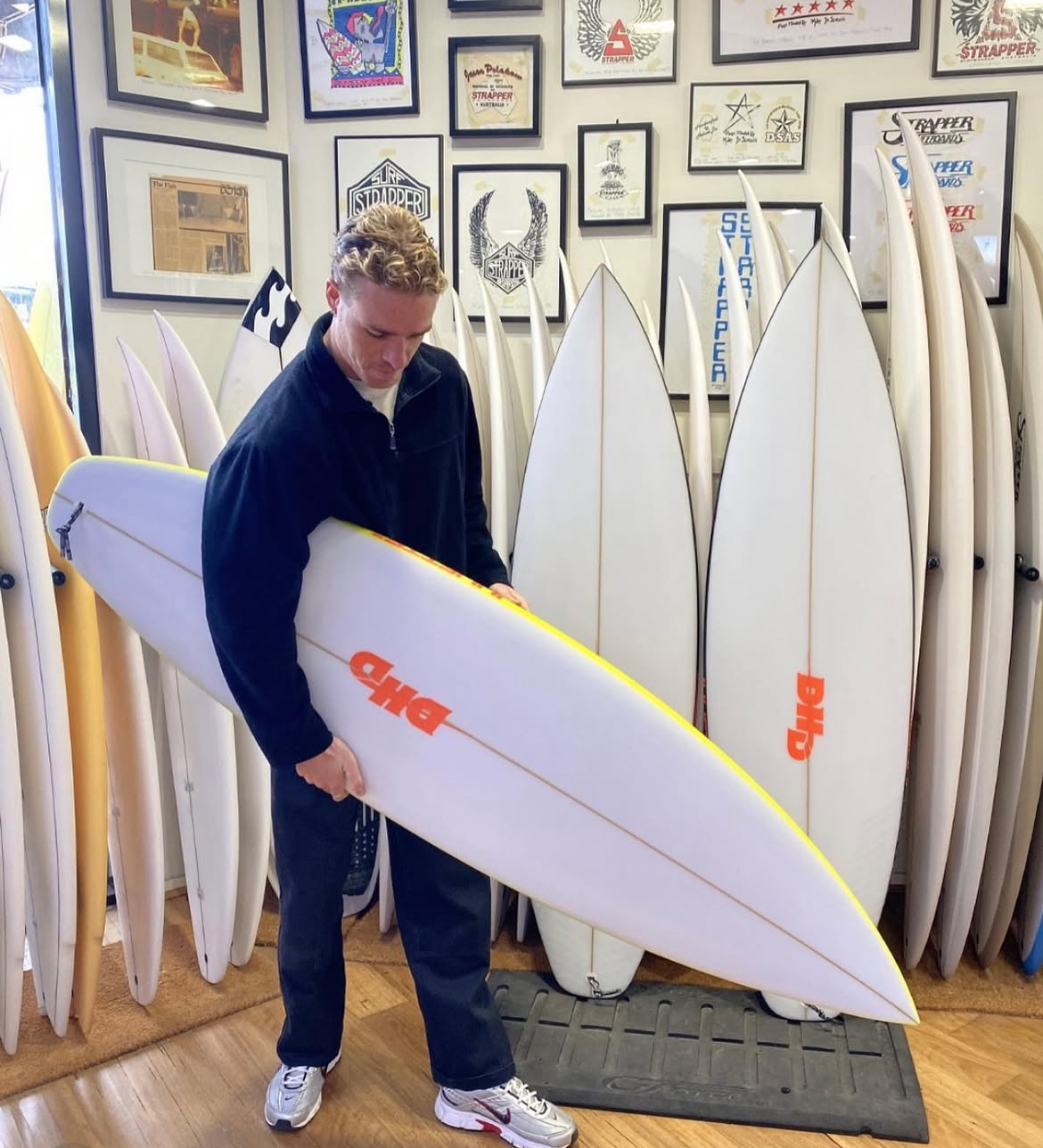 Founder of Core Surf Academy holding a surfboard in a surf shop